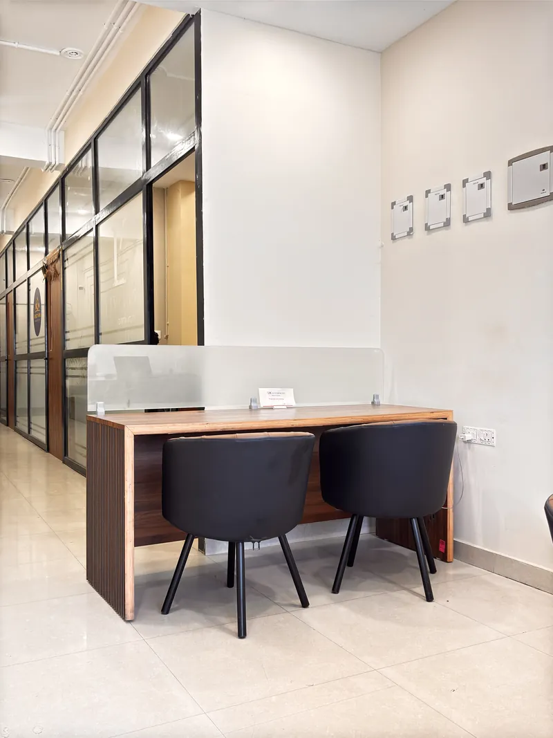 Two-seat coworking desk with frosted divider and wall charging point